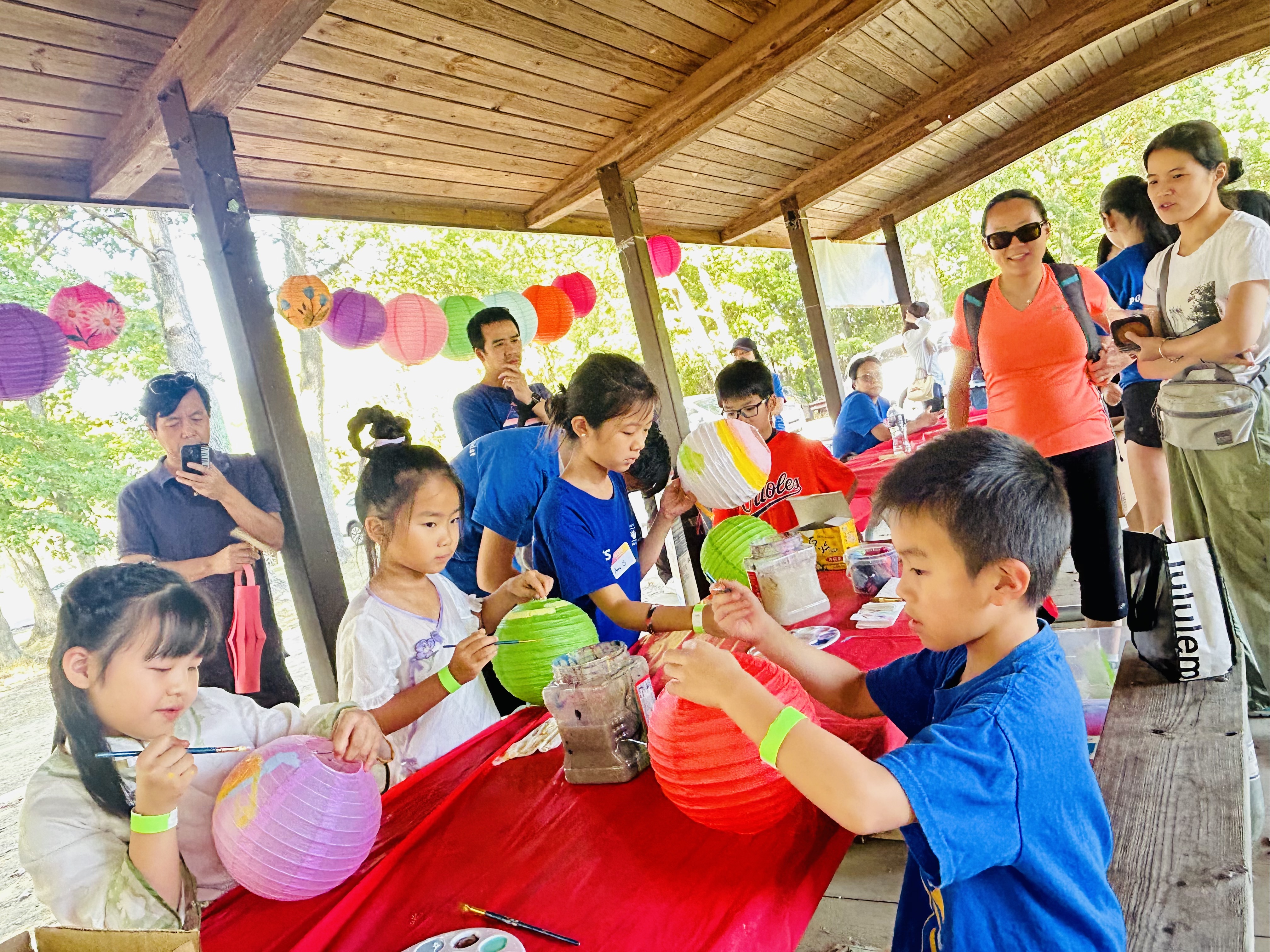Children and adult volunteers painting colorful lanterns at a PCA Youth Center community event